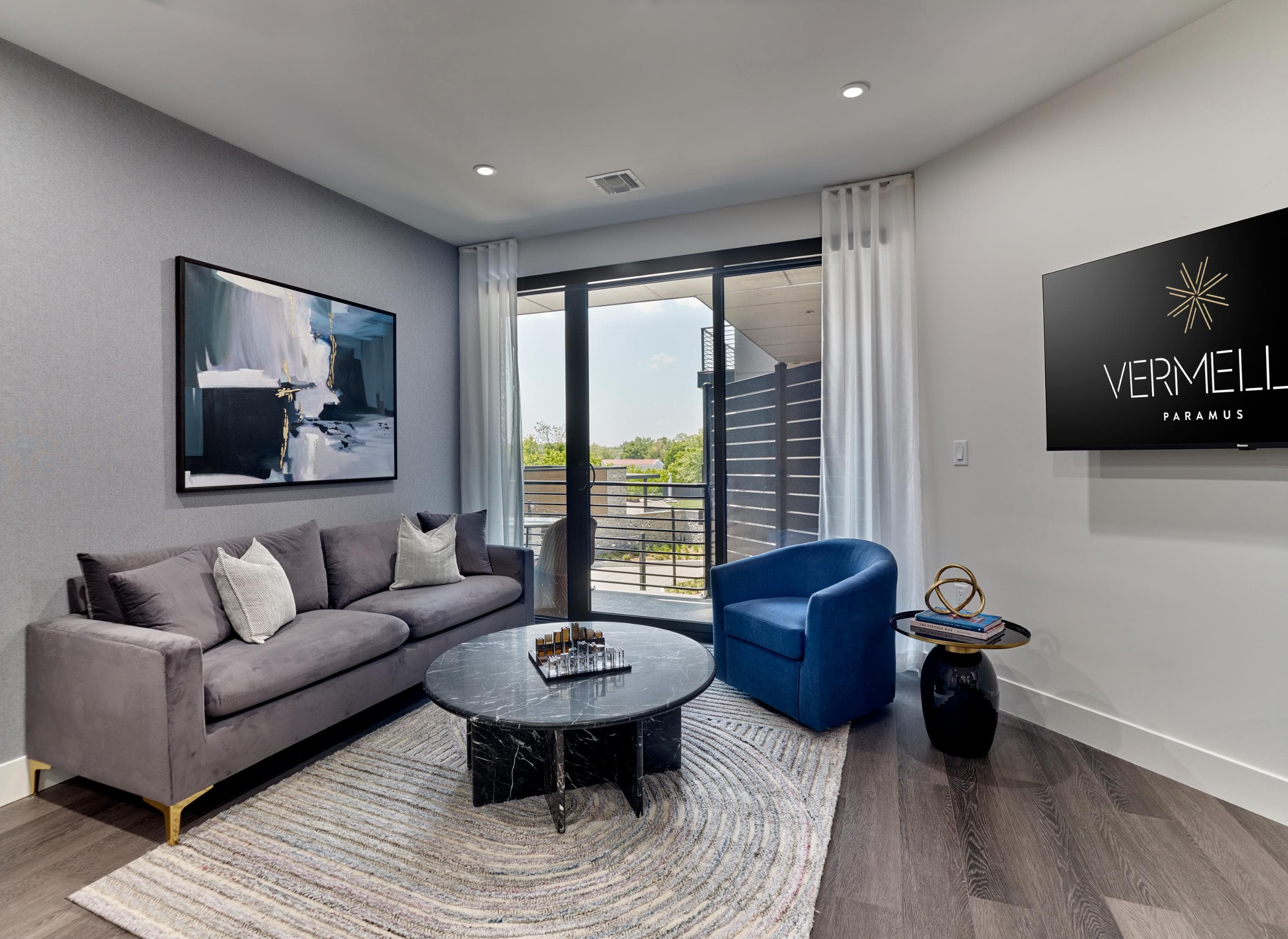 A living room with a grey couch, a black coffee table, and a blue chair.