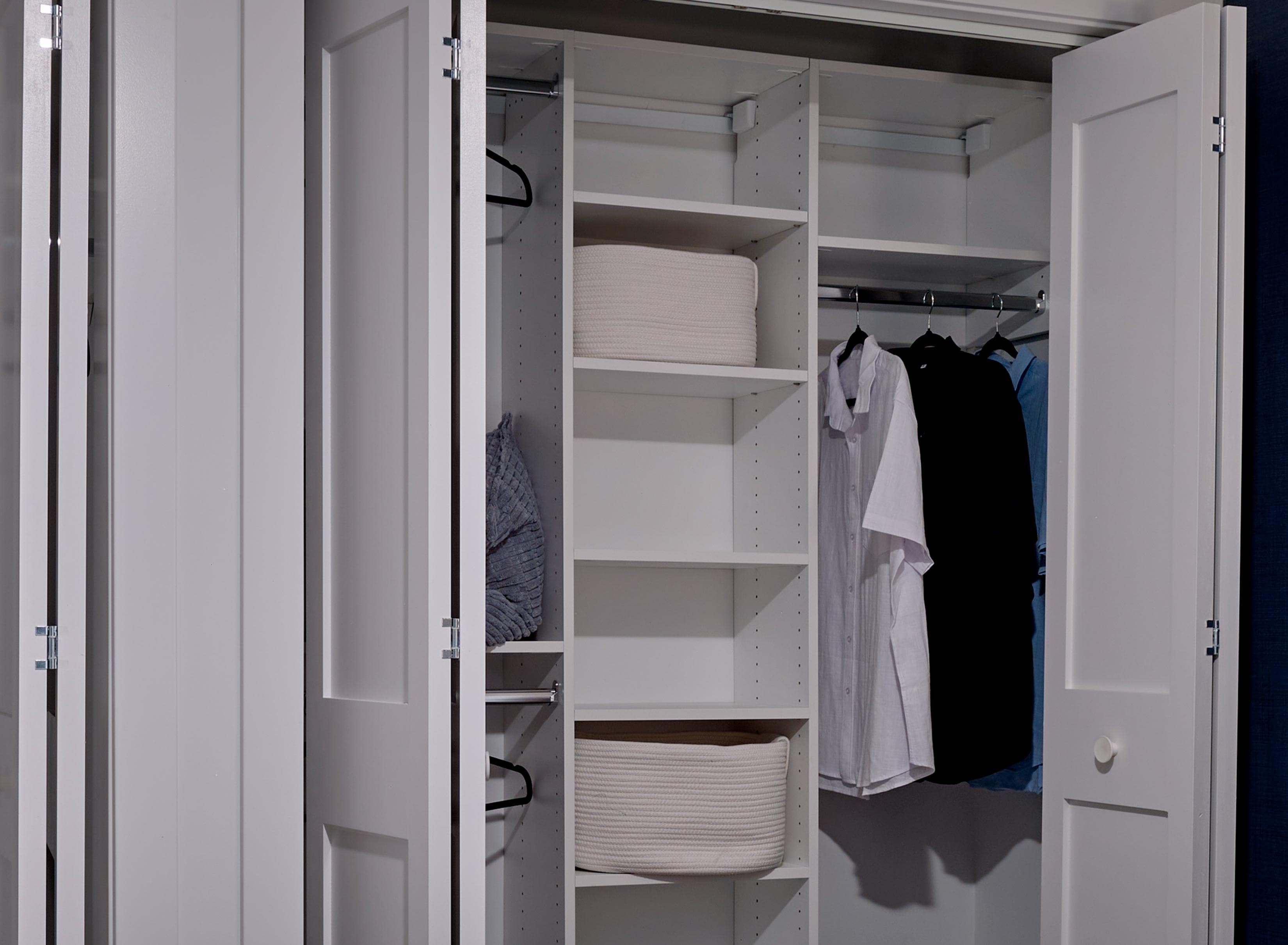 A white closet with clothes hanging and shelves.