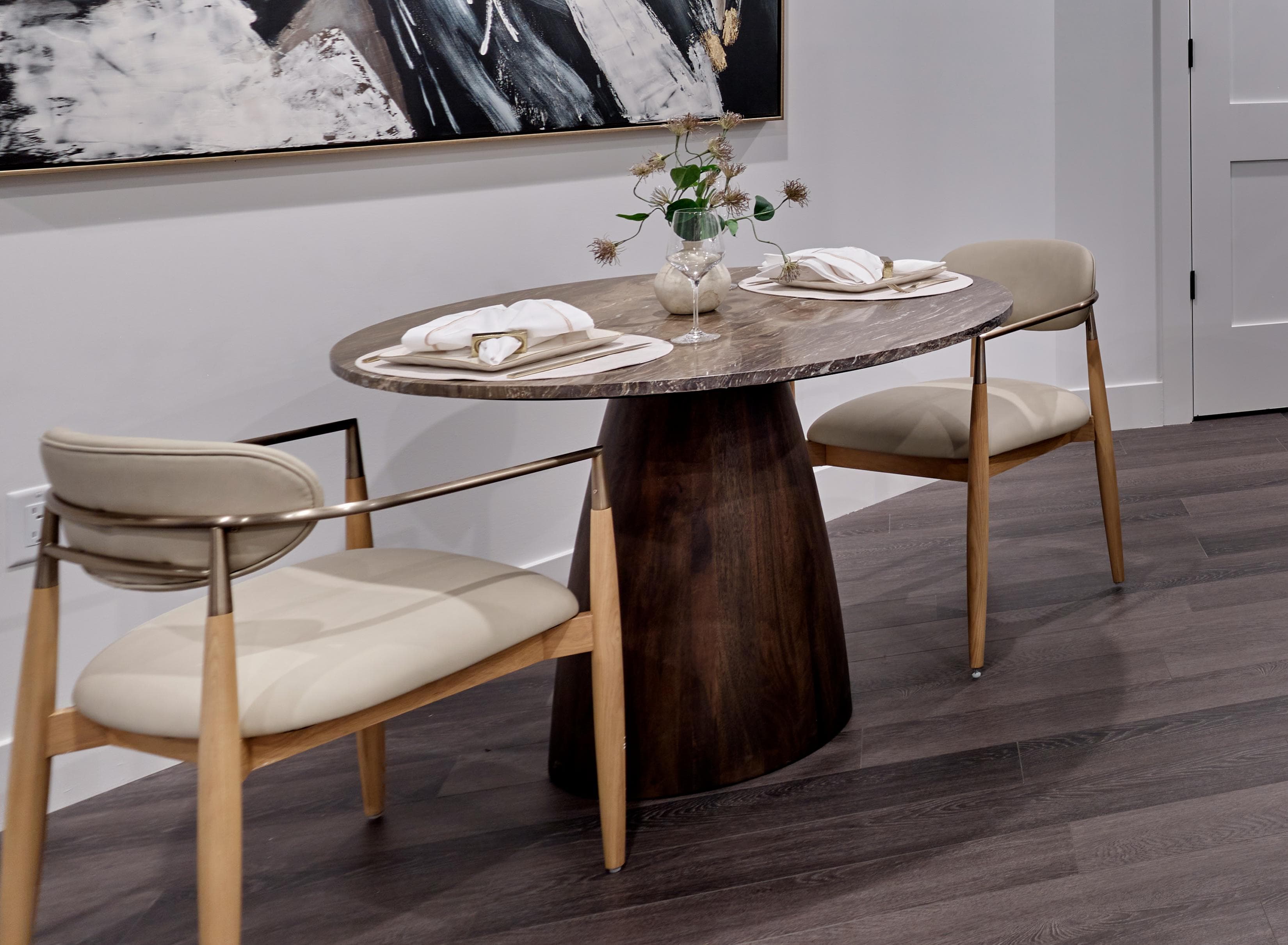 A wooden table with two chairs and a vase with flowers on top.