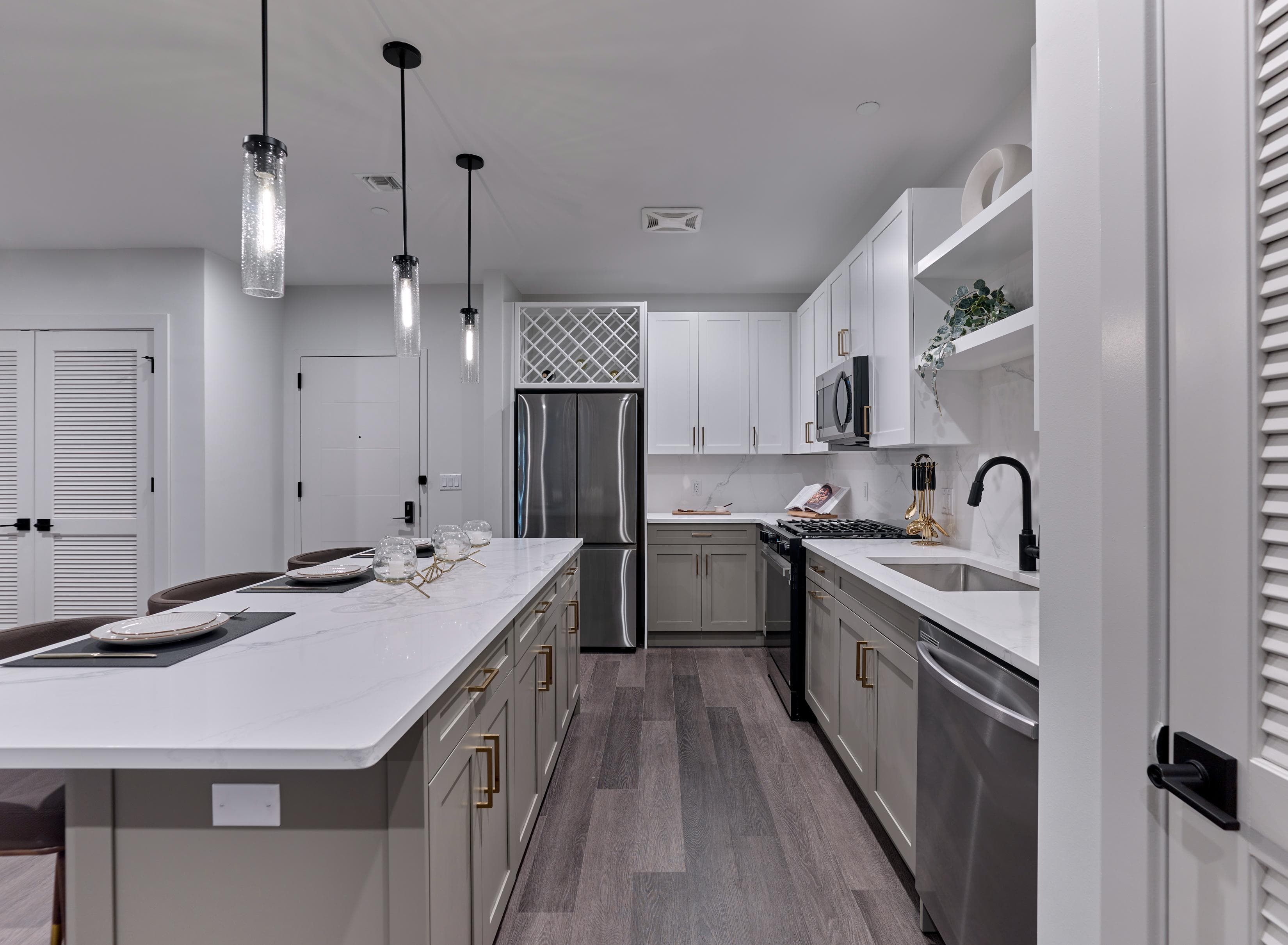 A modern kitchen with a white countertop and dark wood flooring.