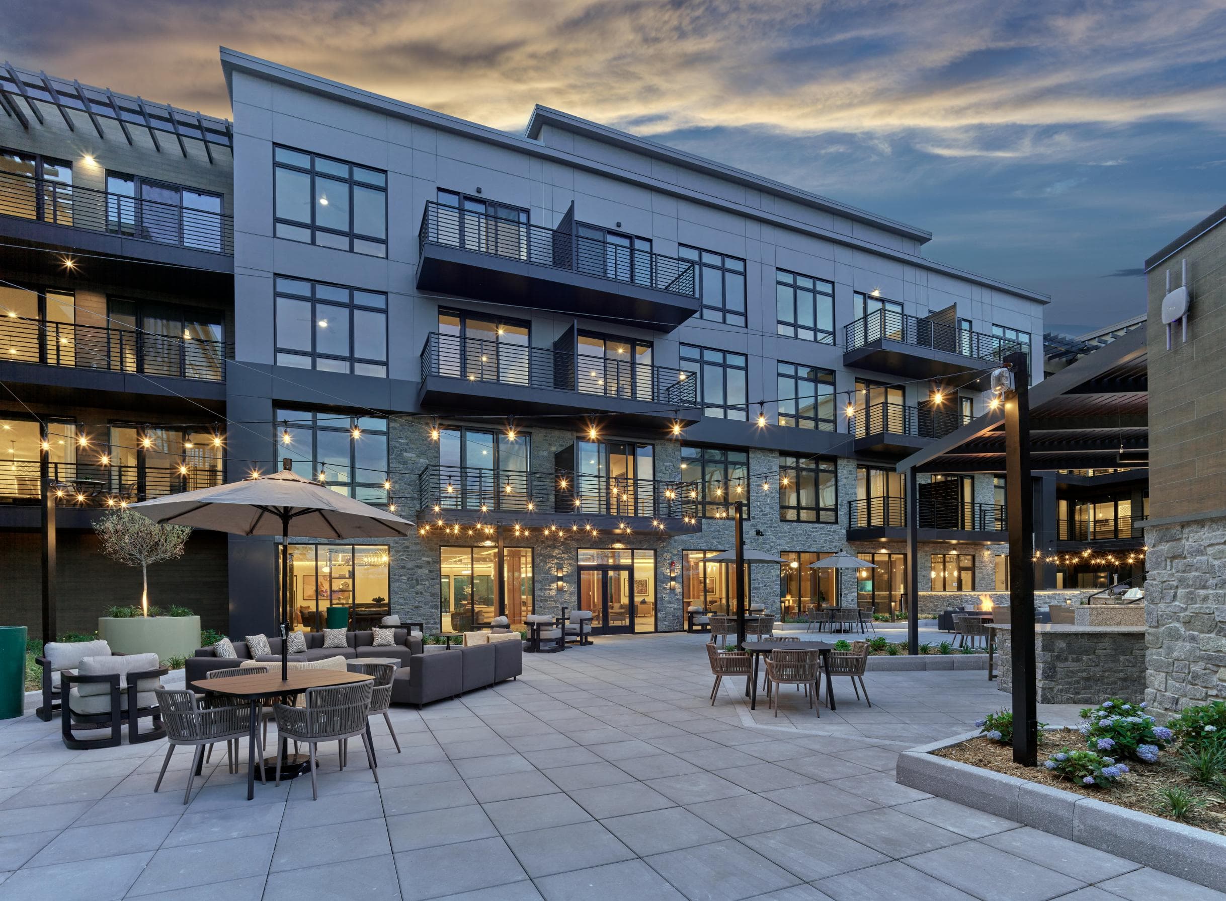A modern apartment community with a patio and tables.