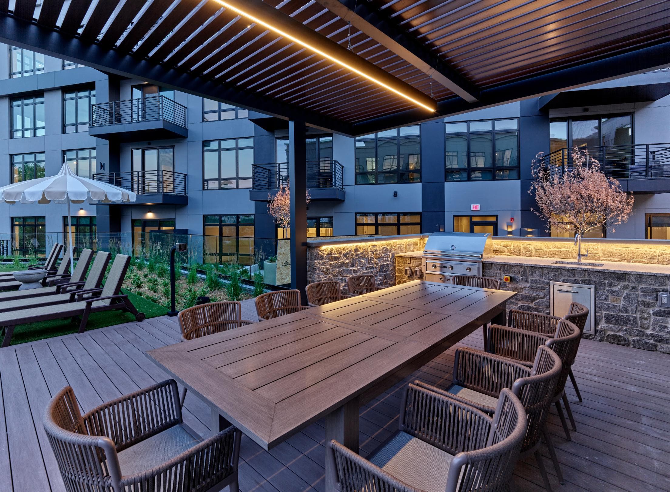 A dining table surrounded by chairs on a deck in a luxury apartment community with resort-style pool.