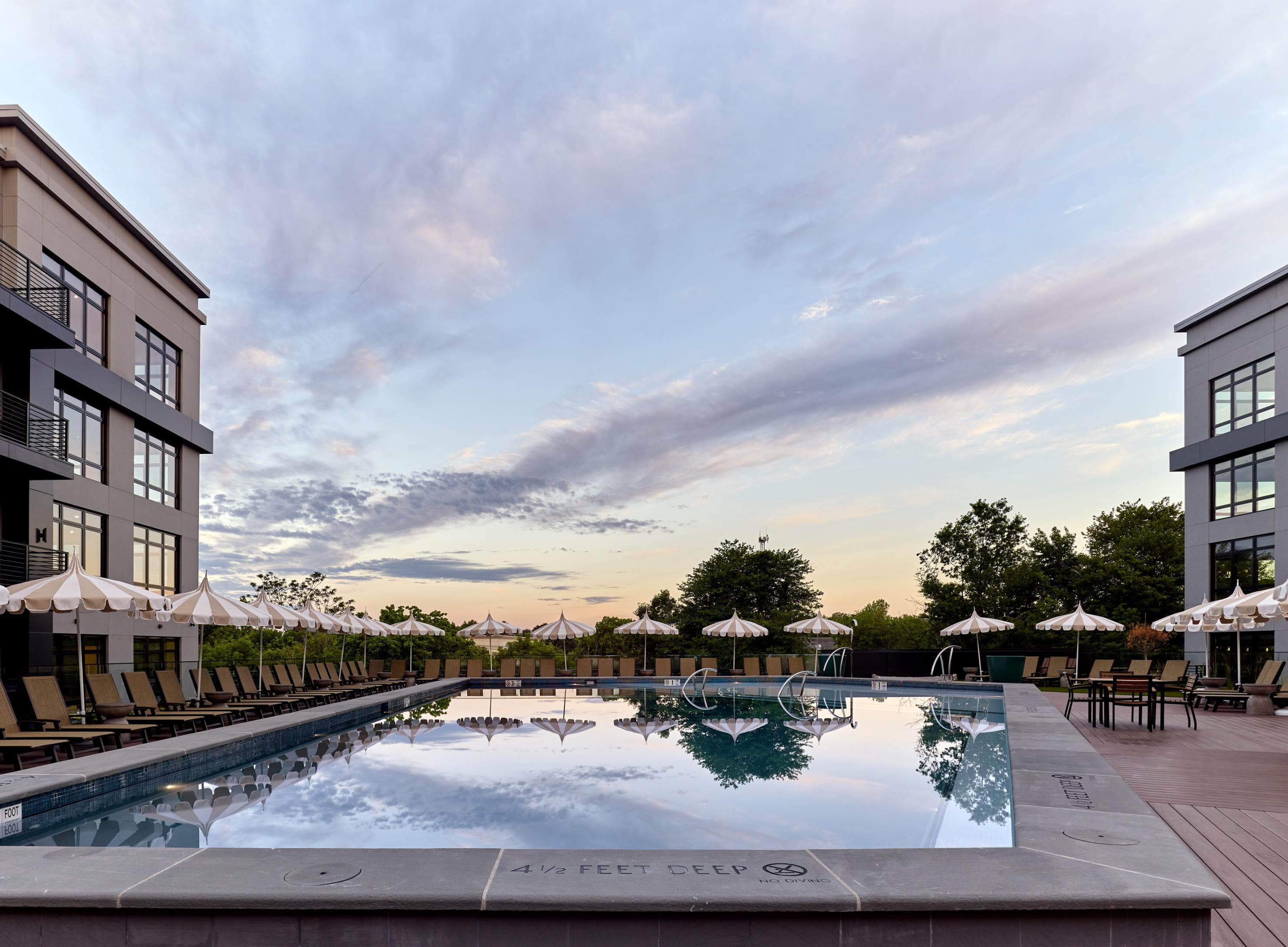 A large swimming pool surrounded by lounge chairs and umbrellas.