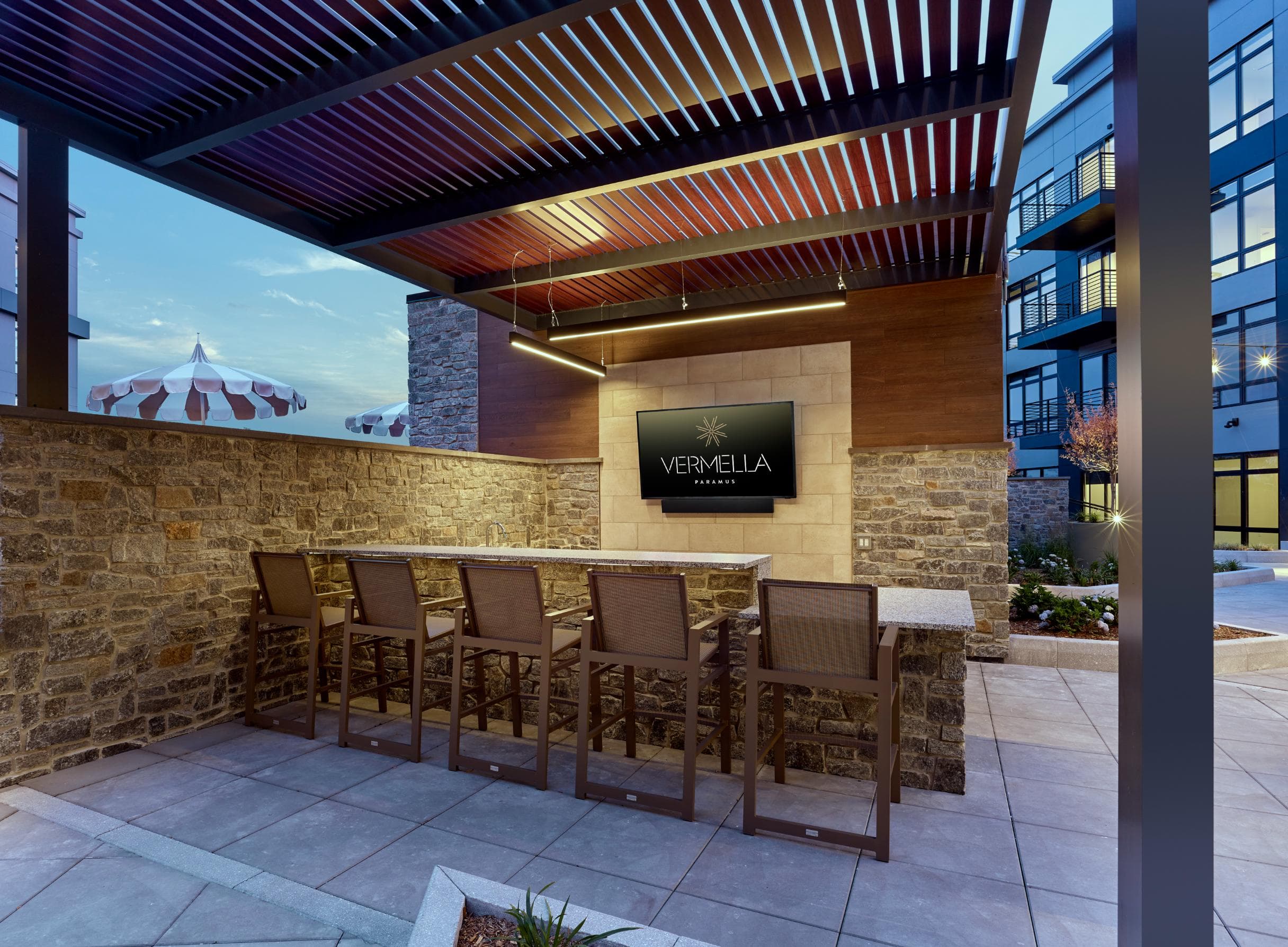 A patio area with a table and chairs in front of a stone wall and a sign that says