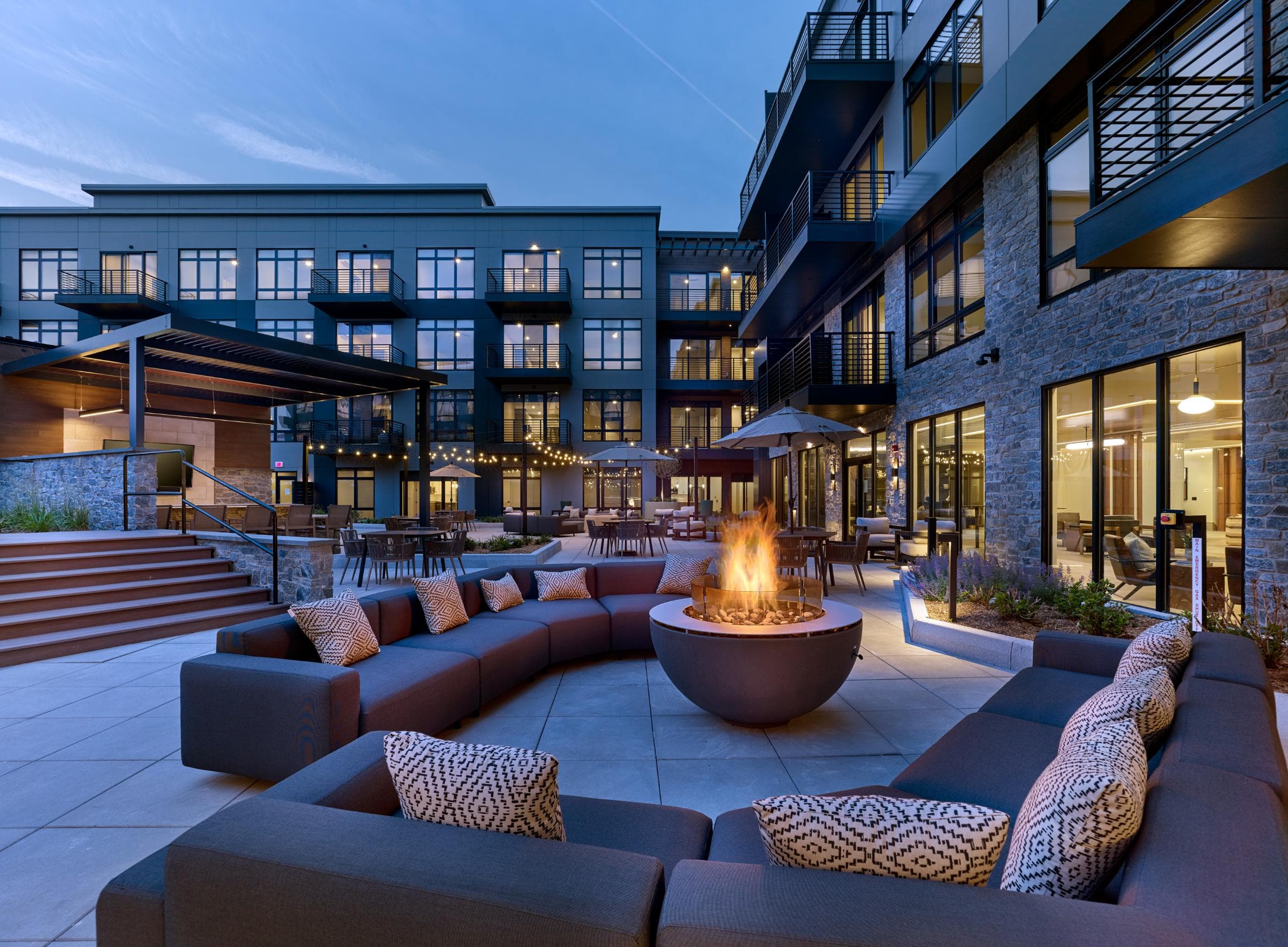 A modern outdoor seating area with a fire pit in the center.