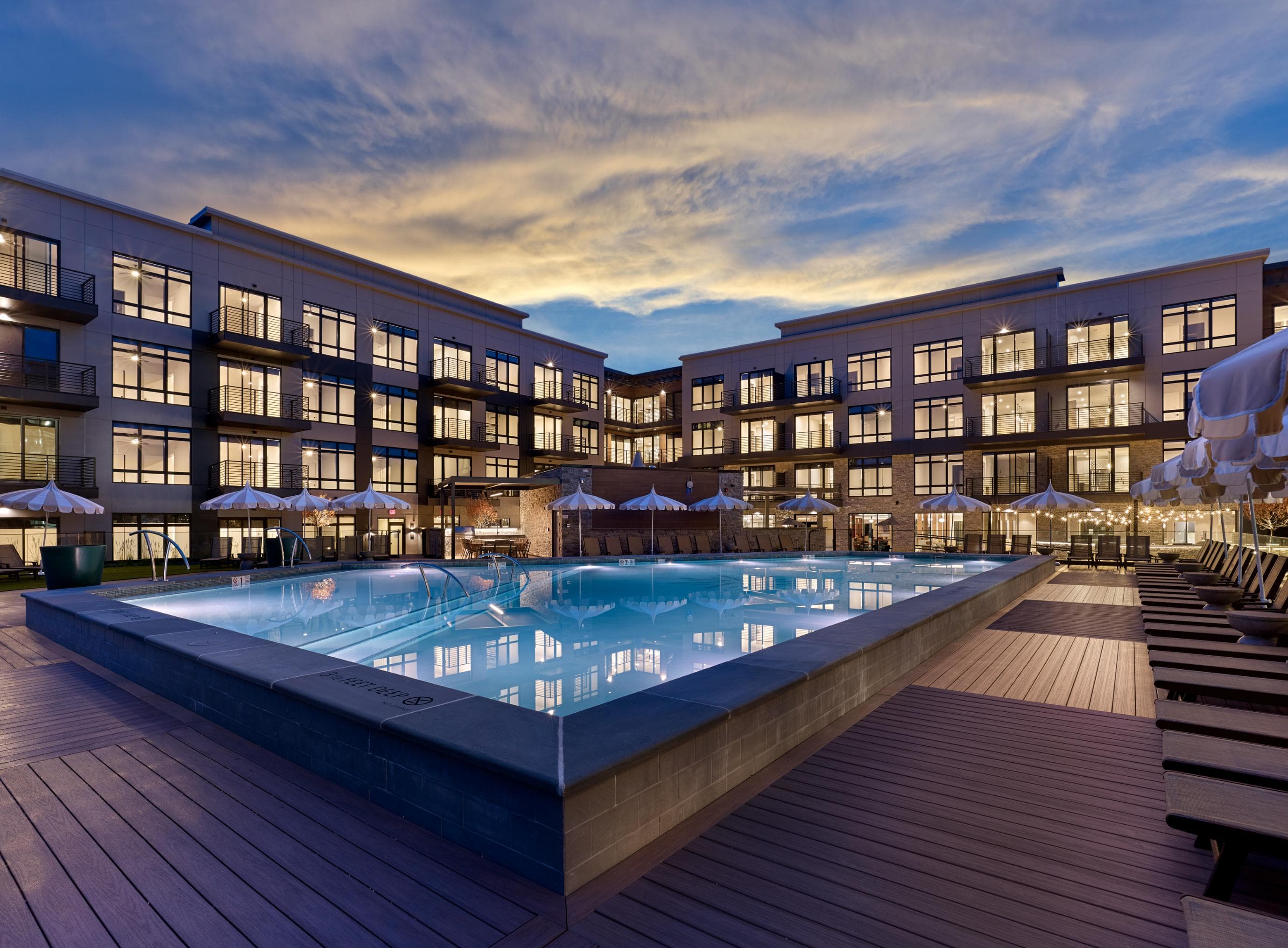 A large outdoor swimming pool surrounded by wooden decking and lounge chairs.
