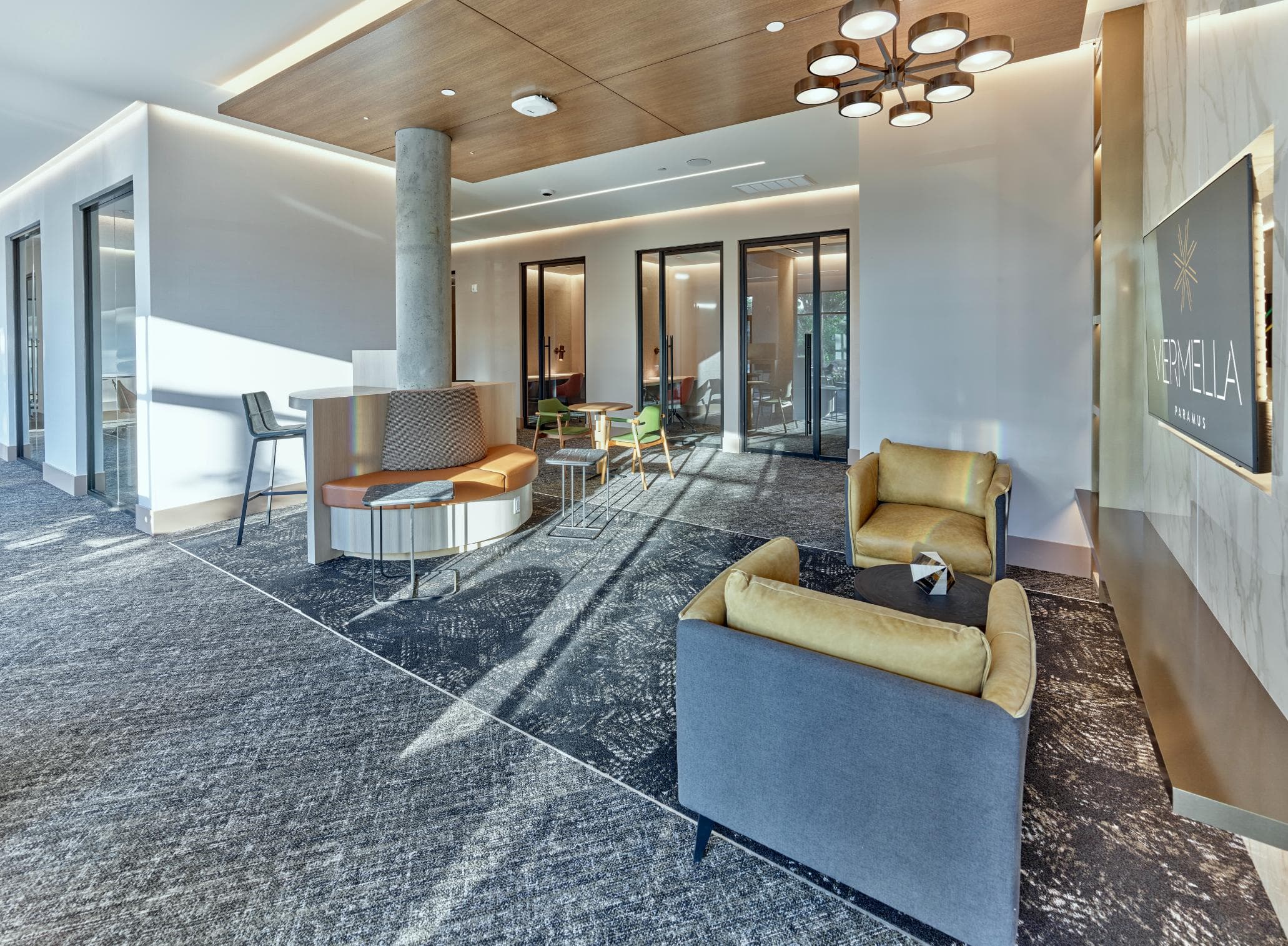A modern living room with a grey carpet and a wooden ceiling.