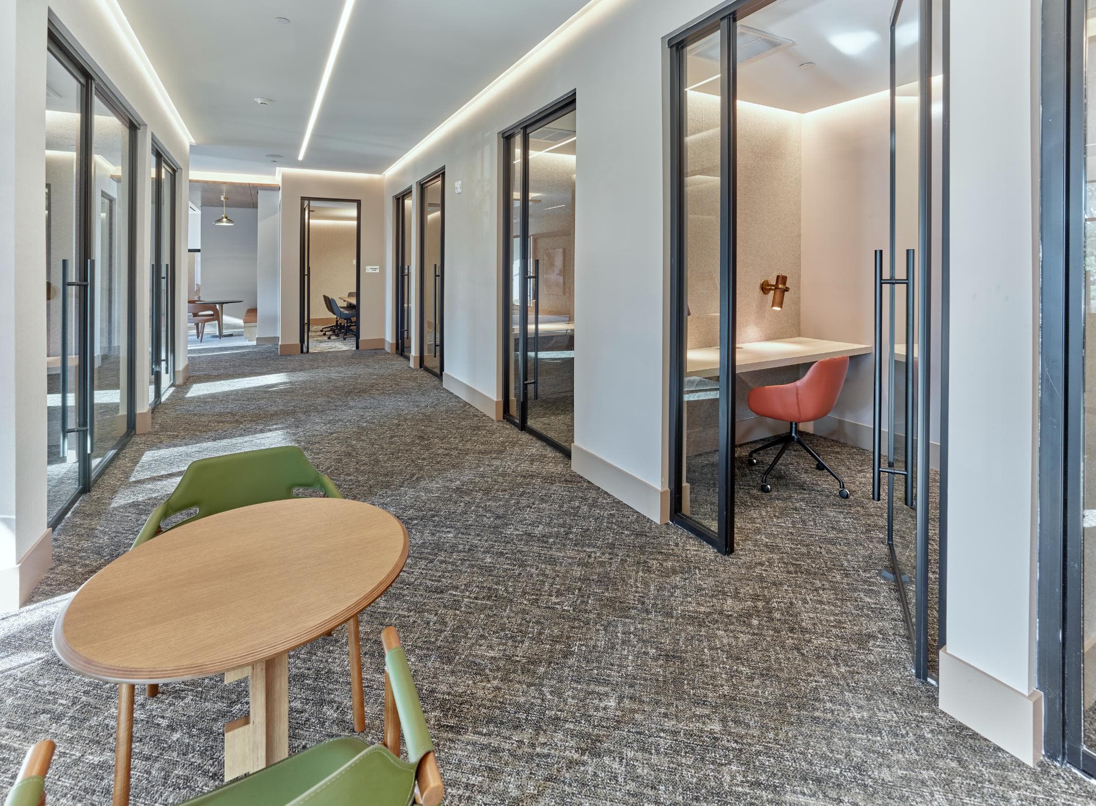 A long hallway with a table and chairs on the left side.